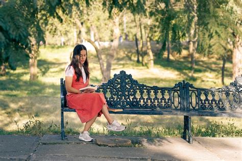 Premium Photo Mujer Latina Sentada En Una Banca De Un Parque Leyendo Un Libro