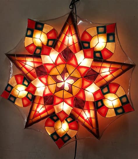 a red and yellow star shaped light hanging from a ceiling fixture with lights on it