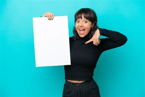 Jovem mulher latina isolada em fundo azul segurando um cartaz vazio expressão feliz e