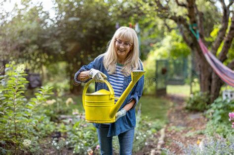 Mature Woman Watering Plants In Her Garden Stock Image Image Of Woman Older 337799489