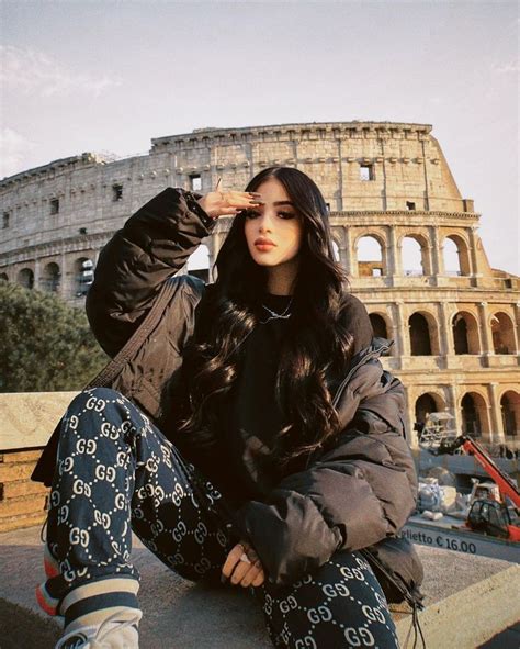 A Woman Sitting On The Ground In Front Of An Old Building And Looking