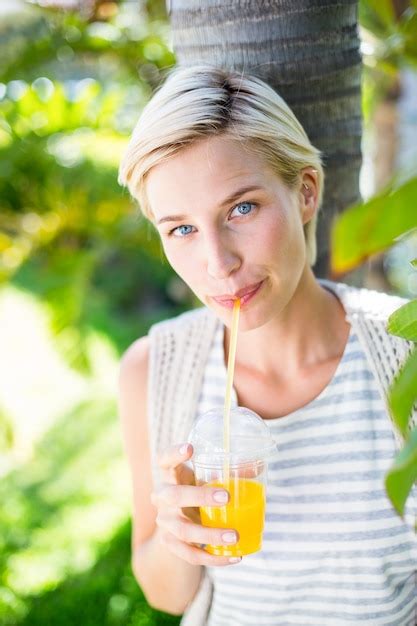 Premium Photo Pretty Blonde Woman Smiling At The Camera And Drinking Orange Juice