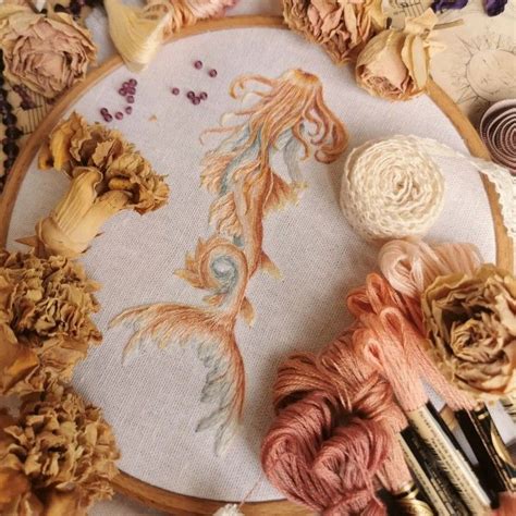 A Close Up Of A Cross Stitch Pattern On A Table With Yarns And Flowers