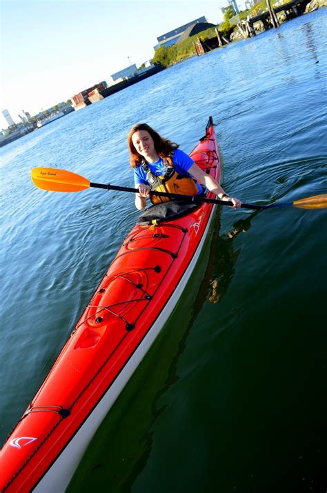 a woman in a red kayak paddles through the water on a sunny day