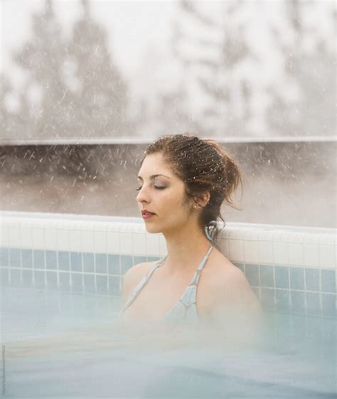 Woman Relaxing In Hot Tub With Her Eyes Closed At Resort In The Winter While It Is Snowing By