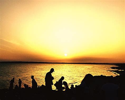 Premium Photo | Silhouette people sitting on beach against orange sky