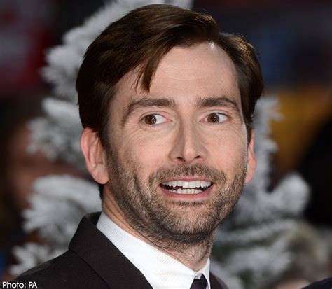 a man in a suit and tie smiles at the camera while standing next to a ...