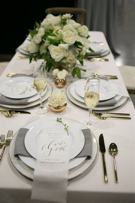 the table is set with white flowers and silverware for an elegant ...