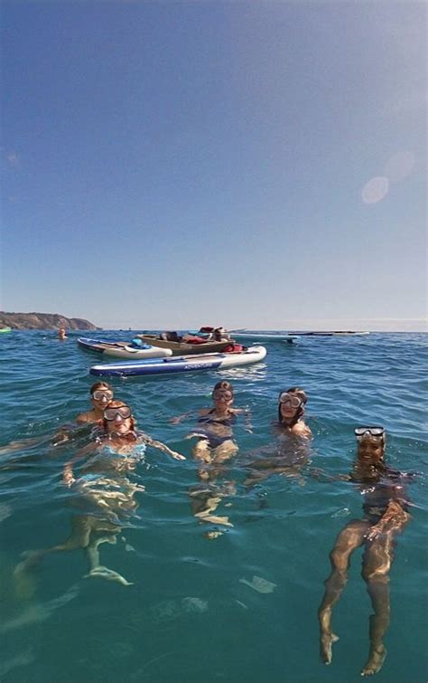 Several People Are Swimming In The Water Near A Boat