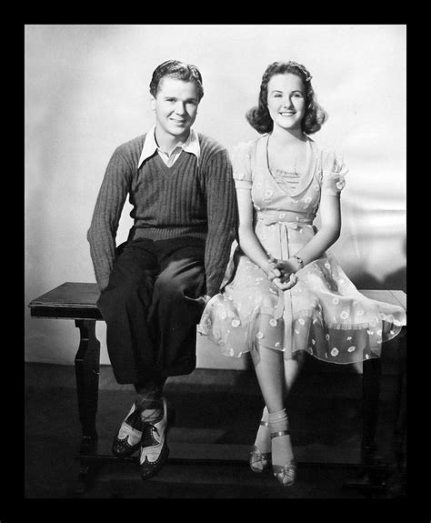 An Old Photo Of A Man And Woman Sitting Next To Each Other On A Bench