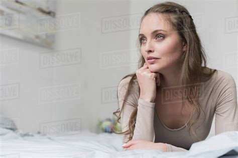 Attractive Woman Lying On A Bed And Looking Away Stock Photo Dissolve