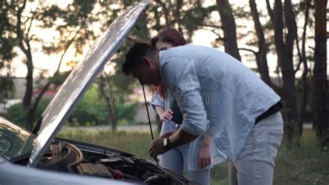 Side View Portrait Of Focused Man Leaning At Open Car Hood Talking With