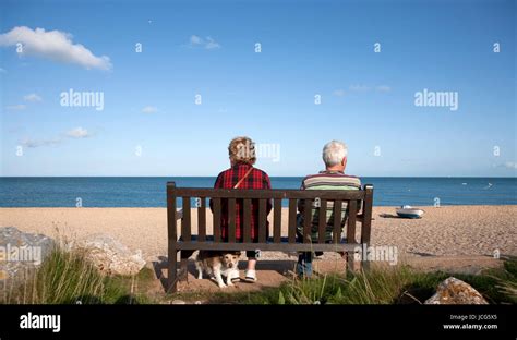 Male And Female Pensioners Old Couple Sitting On Bench Looking Out To