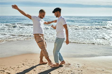 Jovem Casal Gay Sorrindo Feliz Dançando Na Praia Imagem de Stock