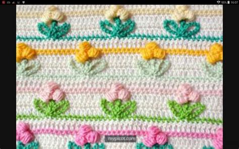 A Crocheted Blanket With Flowers And Leaves On The Side In Pink Green