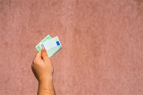 Premium Photo Cropped Hand Of Man Holding Paper Currency Against Wall