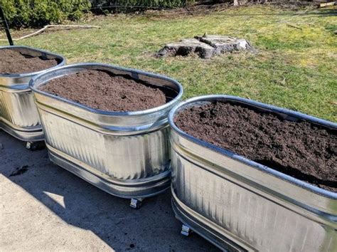 three metal containers filled with dirt sitting on top of a sidewalk