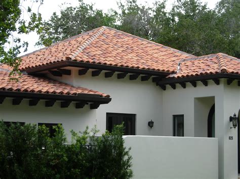 A White House With Red Tile Roofing Next To Trees