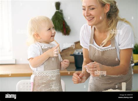 Petite fille et sa maman blonde en rouge et rire tout en jouant des tabliers le pétrissage la