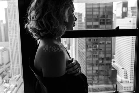 Woman In Black Silk Robe Lies With Naked Shoulders Before A Panoramic Window In New York Stock