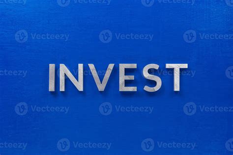 The Word Invest Laid With Silver Metal Characters On Blue Painted