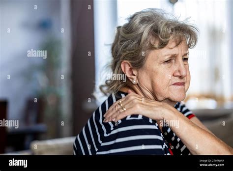 Portrait Of Senior Woman Suffering From Neck Pain While Sitting On Sofa