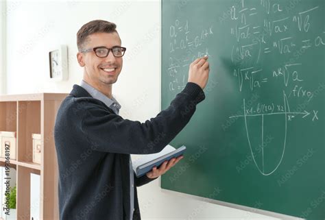 Young male teacher writing on blackboard in classroom Stock Photo ... 