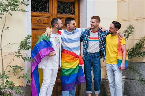 Oyful Group Of Four Gay Friends Embracing Walking Out Of Their Home Adorned With Lgbt Pride