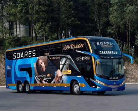 A Blue And Yellow Double Decker Bus Driving Down The Road With Trees In