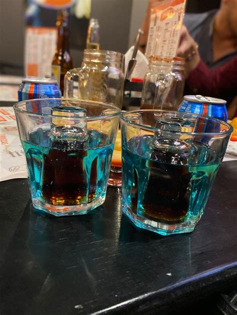 Two Glasses Filled With Blue Liquid Sitting On Top Of A Table Next To