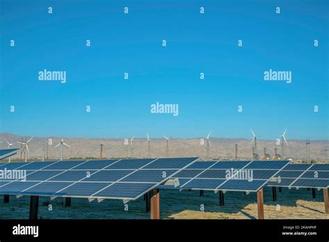 Solar Panels With Windmills Blue Sky And Mountain In The Background