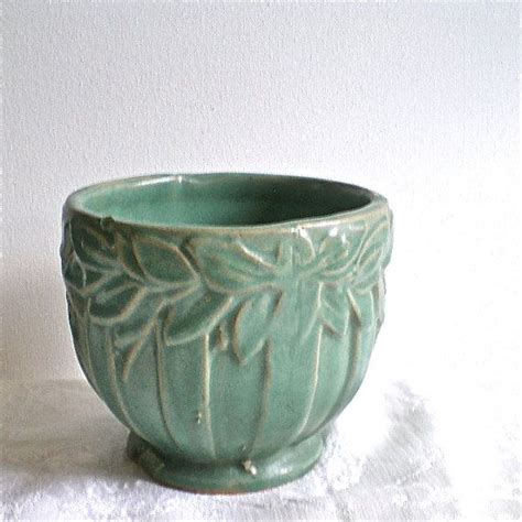 A Green Bowl Sitting On Top Of A White Cloth Covered Table Next To A Wall