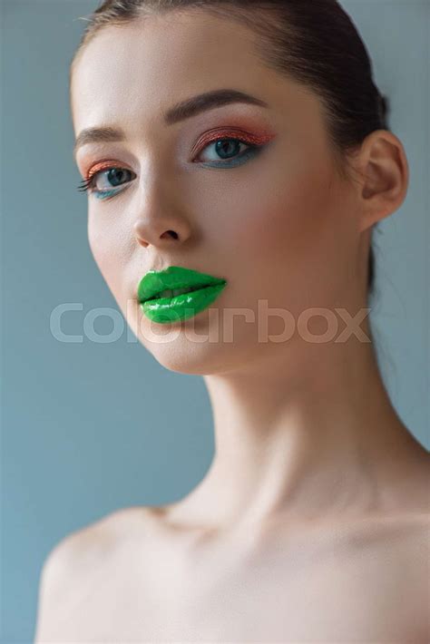 Portrait Of Beautiful Naked Woman With Green Lips Pink And Blue Eyeshadow Isolated On Blue