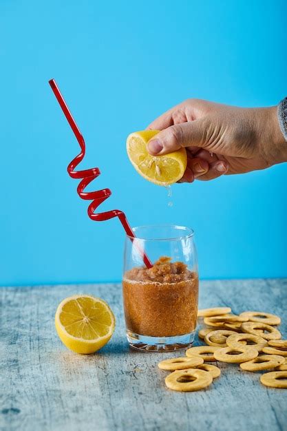 Exprimir limón fresco en un vaso de jugo con pajita y galletas en la