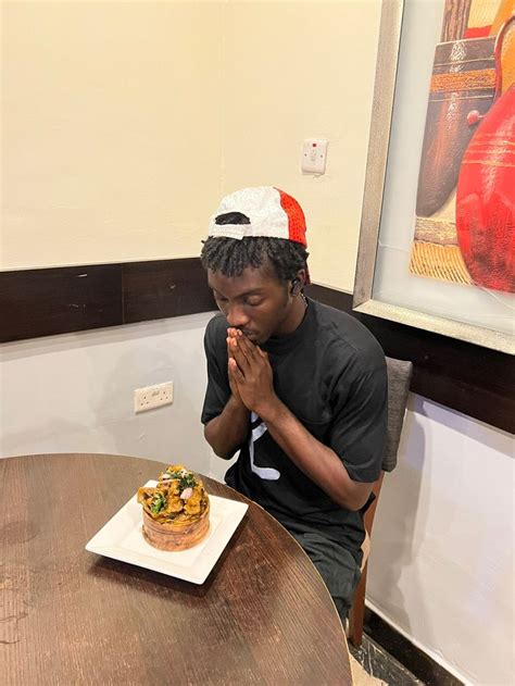 A Man Sitting At A Table In Front Of A Cake With Toppings On It