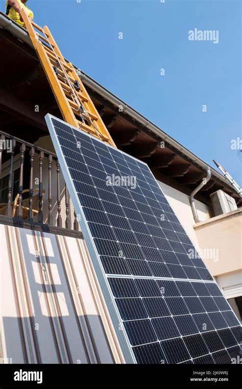 Worker Lifting Solar Panel Up Ladder To Rooftop Navarre Spain Europe