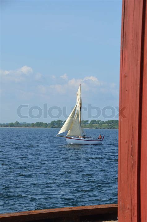 hvidt sejlskib på havet med med mast og hvide sejl i blå bølger og blå