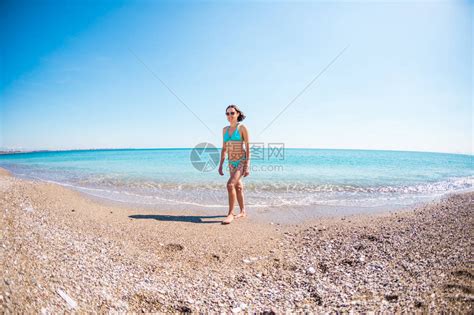 一个穿着泳衣的女人走在石滩上女孩看着大海布鲁内特在地中海的滩上休息土耳其的寒假女孩高清图片下载 正版图片506094882 摄图网