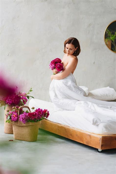 Topless Woman With A Bouquet Of Peonies In A Blanket On The Bed Stock