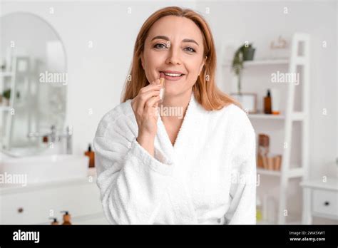 Mature Woman Applying Lipstick After Shower In Bathroom Stock Photo Alamy