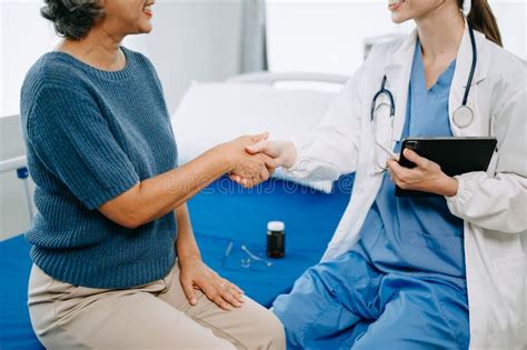 Doctor And Senior Female Patient Who Lie On The Bed While Checking