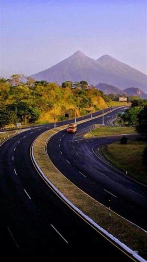 An Empty Highway With Mountains In The Background