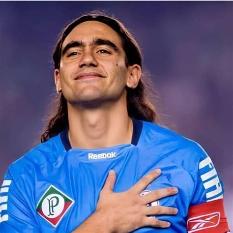 A Man With Long Hair Wearing A Blue Shirt And Holding His Arms Around