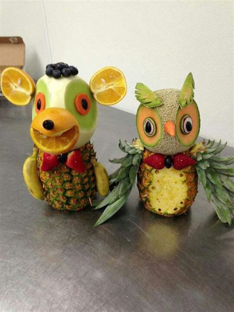 Two Fruit Sculptures Made To Look Like Animals Sitting Next To Each