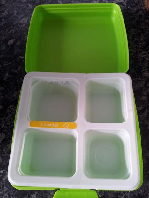 A Green And White Plastic Lunch Box With Four Compartments On The Top