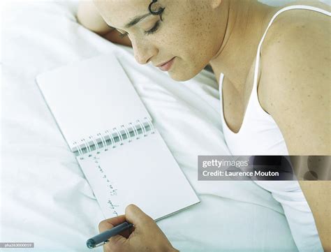 Woman Lying On Side On Bed Writing In Notebook With Pen High Res Stock