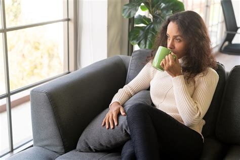 Mulher latina tomando café no sofá Foto Premium