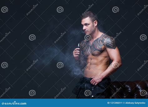 Vaper The Man With A Muscular Naked Torso With Tattoos Smoke An