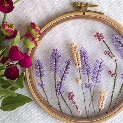 A Close Up Of A Embroidery On A Table With Flowers In Front Of The Hoop