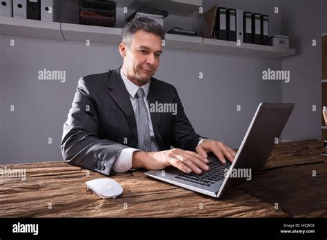 Mature Businessman Working On Laptop At Workplace Stock Photo Alamy